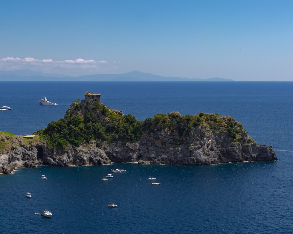 a rocky island with boats with Isola Bella in the background